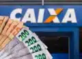Dinheiro em notas de real em frente a uma agência da Caixa Econômica Federal, representando a solicitação do saque de R$ 6.220.