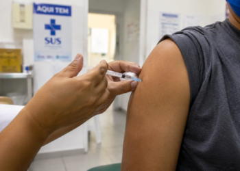 Pessoa recebendo vacina no braço em posto de saúde, em imagem relacionada à análise da Anvisa sobre a Butantan-DV contra a dengue.