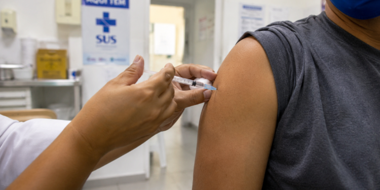 Pessoa recebendo vacina no braço em posto de saúde, em imagem relacionada à análise da Anvisa sobre a Butantan-DV contra a dengue.