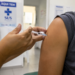 Pessoa recebendo vacina no braço em posto de saúde, em imagem relacionada à análise da Anvisa sobre a Butantan-DV contra a dengue.