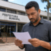 Homem analisando documento em frente a prédio de prefeitura municipal.