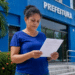 Mulher lê documento de concurso público em frente à Prefeitura Municipal.