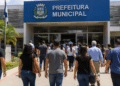 Grupo de pessoas caminha em direção à Prefeitura Municipal em imagem sobre concursos com salários acima de R$ 7 mil.