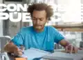 Candidato de camiseta azul estudando com caderno e apostila após o resultado final da 2ª edição do CNU
