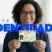Mulher sorridente com óculos segura nova carteira de identidade brasileira com texto grande “NOVA IDENTIDADE”.