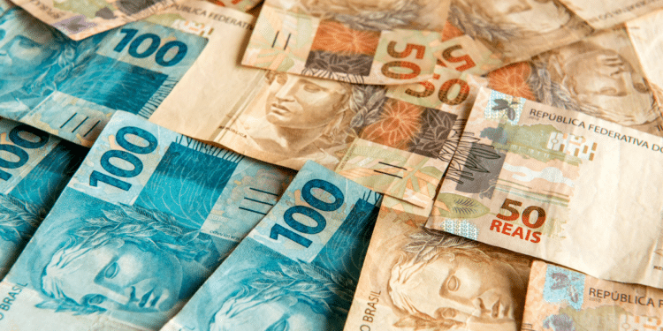Notas de 50 e 100 reais espalhadas sobre superfície.