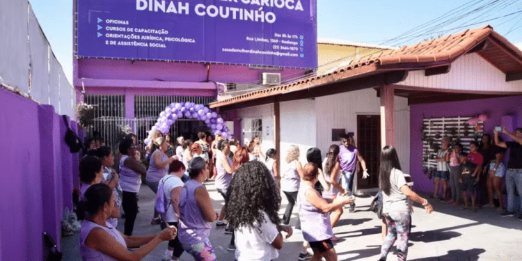 Mulheres vestidas de blusas roxas reunidas em ambiente externo.