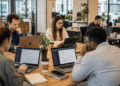 Grupo diverso de seis pessoas reunidas em coworking moderno, usando laptops abertos no ChatGPT.