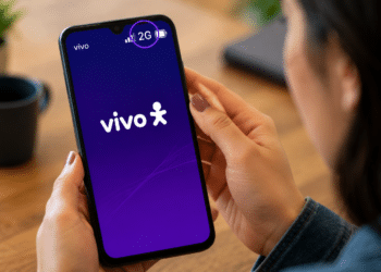 Mulher segura smartphone com tela inicial Vivo mostrando sinal 2G destacado.
