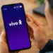 Mulher segura smartphone com tela inicial Vivo mostrando sinal 2G destacado.