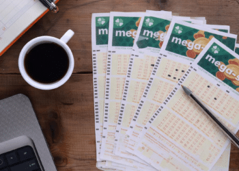 Volantes da Mega-Sena organizados sobre mesa com café e caneta.