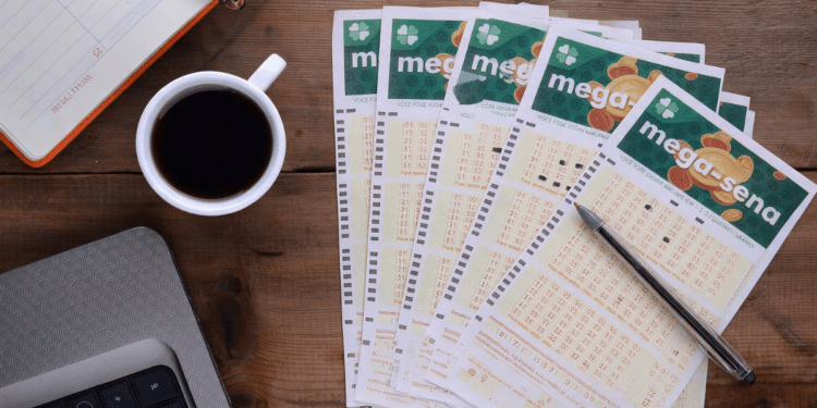Volantes da Mega-Sena organizados sobre mesa com café e caneta.
