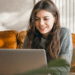Jovem sorridente usando notebook em ambiente aconchegante.