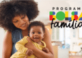 Mulher negra segurando bebê sorridente no colo ao lado do logo colorido do Programa Bolsa Família.