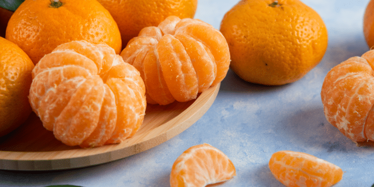 Tangerinas frescas inteiras e descascadas em fundo azul claro.