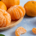 Tangerinas frescas inteiras e descascadas em fundo azul claro.