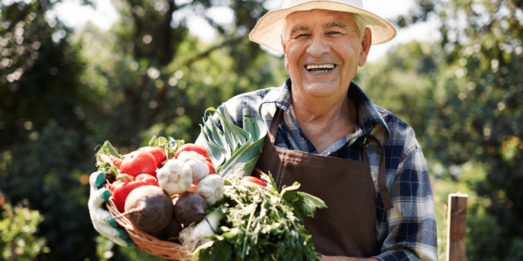 Homem sorridente em uma plantação e segurando cesta.