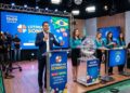 Apresentador e equipe realizam sorteio da Loteria dos Sonhos ao vivo, com globos e esfera