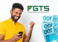 Homem sorrindo com celular na mão diante do logo FGTS e notas de cem reais.