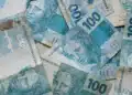 Notas de R$ 100 do real brasileiro sobrepostas, ilustrando a liberação do abono salarial PIS/Pasep no mês de julho.