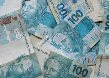 Notas de R$ 100 do real brasileiro sobrepostas, ilustrando a liberação do abono salarial PIS/Pasep no mês de julho.