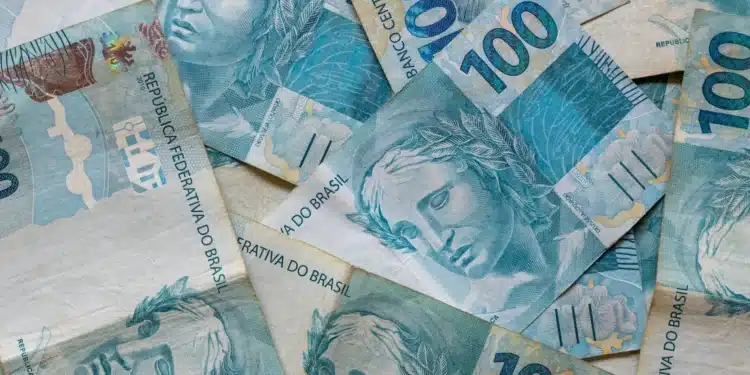 Notas de R$ 100 do real brasileiro sobrepostas, ilustrando a liberação do abono salarial PIS/Pasep no mês de julho.