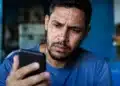 Usuário preocupado consultando o celular, representando os golpes envolvendo falsos anúncios do Desenrola Brasil nas redes sociais.