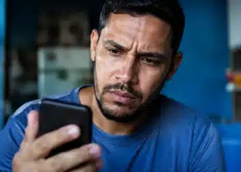 Usuário preocupado consultando o celular, representando os golpes envolvendo falsos anúncios do Desenrola Brasil nas redes sociais.
