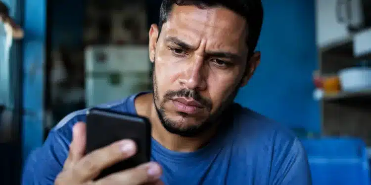 Usuário preocupado consultando o celular, representando os golpes envolvendo falsos anúncios do Desenrola Brasil nas redes sociais.