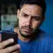 Usuário preocupado consultando o celular, representando os golpes envolvendo falsos anúncios do Desenrola Brasil nas redes sociais.