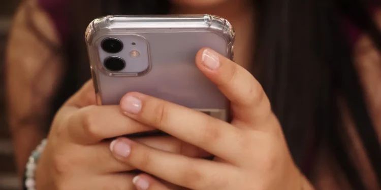 Usuária segurando smartphone em destaque, representando atualizações de segurança da Apple contra ameaças digitais impulsionadas por inteligência artificial.