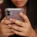 Usuária segurando smartphone em destaque, representando atualizações de segurança da Apple contra ameaças digitais impulsionadas por inteligência artificial.