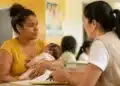 Mãe brasileira segura recém-nascido durante atendimento social, representando as ações necessárias para atualizar o Bolsa Família após o nascimento de um membro ou mudanças na família.