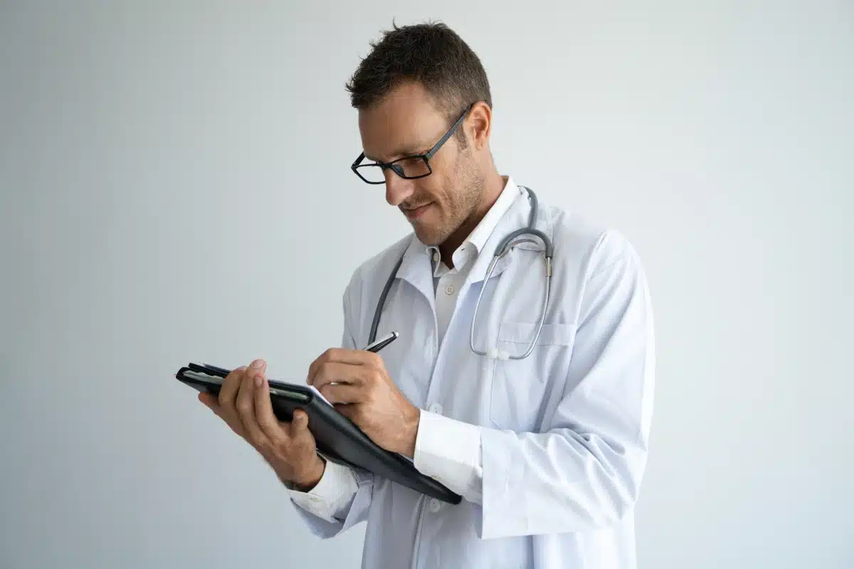 Revalida - Avaliação de conhecimentos e habilidades médicas Médico preenche um prontuário, representando a avaliação de conhecimentos e habilidades clínicas exigida pelo Revalida.