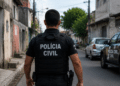 Policial da Polícia Civil de Alagoas caminhando em rua urbana durante operação.