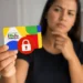Mulher segura cartão do Bolsa Família com símbolo de bloqueio enquanto demonstra dúvida sobre dívidas no SPC e Serasa.