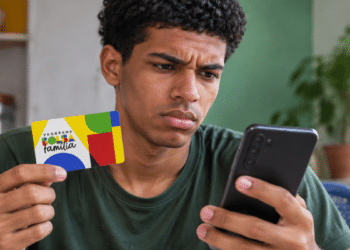 Beneficiário segurando cartão do Bolsa Família e consultando informações no celular.