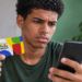 Beneficiário segurando cartão do Bolsa Família e consultando informações no celular.