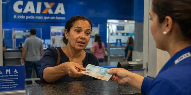 Mulher recebendo cédulas em atendimento na Caixa, representando os depósitos de R$ 300 para 100 mil mulheres em julho.