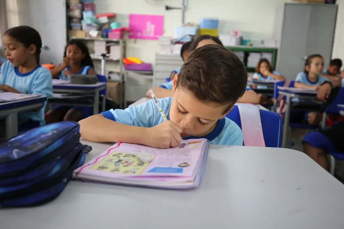 Alunos em sala de aula durante atividade escolar, representando os ajustes no calendário letivo durante a Copa do Mundo Feminina de 2027.