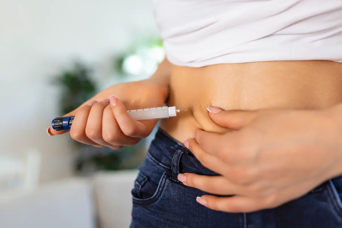 Canetas de semaglutida auxiliam no controle glicêmico Pessoa aplicando caneta injetável no abdômen para representar o uso de medicamentos com semaglutida no controle do diabetes tipo 2.