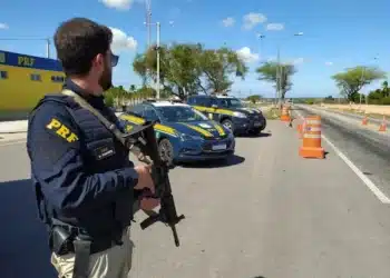 Policial rodoviário federal participa de operação em rodovia com viaturas da PRF.