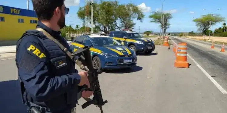 Policial rodoviário federal participa de operação em rodovia com viaturas da PRF.