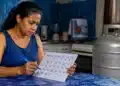 Mulher consultando o calendário do Gás do Povo, representando as datas das próximas recargas gratuitas do benefício em 2026.