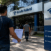 Candidato a concurso público em frente à Receita Federal segurando documento de inscrição ou prova.