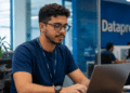 Jovem trabalha em notebook em escritório da Dataprev durante concurso com vagas abertas.