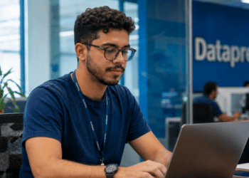 Jovem trabalha em notebook em escritório da Dataprev durante concurso com vagas abertas.