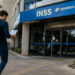 Pessoa caminhando em direção a uma agência do INSS com documentos em mãos, representando a expectativa pelo novo concurso do INSS com 10 mil vagas.