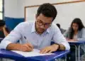 Candidato concentrado preenchendo prova em sala de aula, representando a realização da prova do concurso do Banco do Brasil para o cargo de Escriturário.