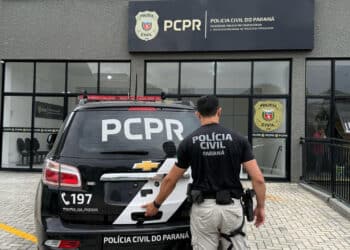 Policial civil do Paraná em frente à viatura e à unidade da PCPR.